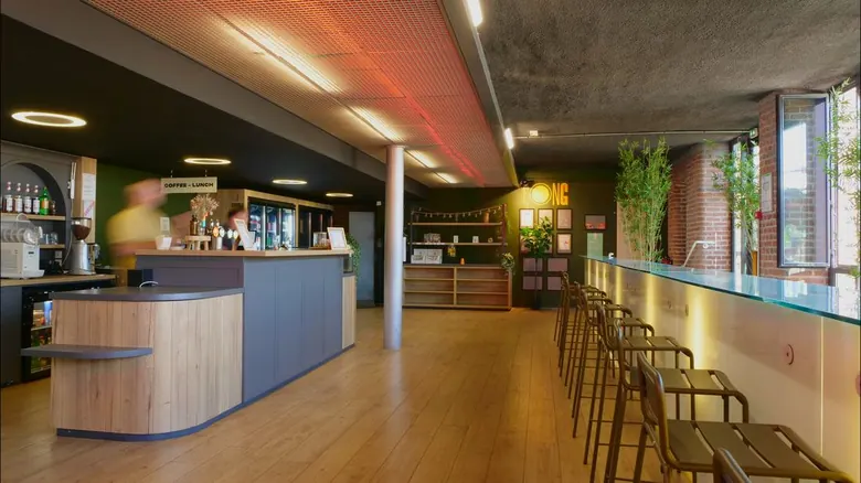 Long comptoir du bar intérieur avec enseigne néon LONG et bouteilles en fond