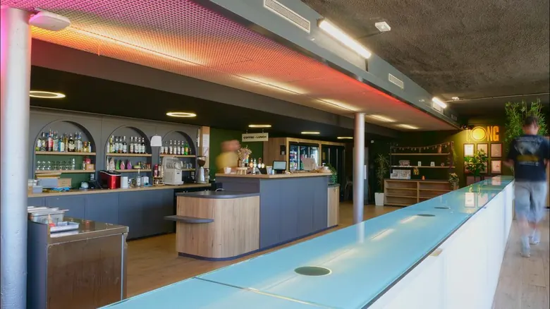 Comptoir du bar vu en enfilade derrière une paroi vitrée, ambiance chaleureuse