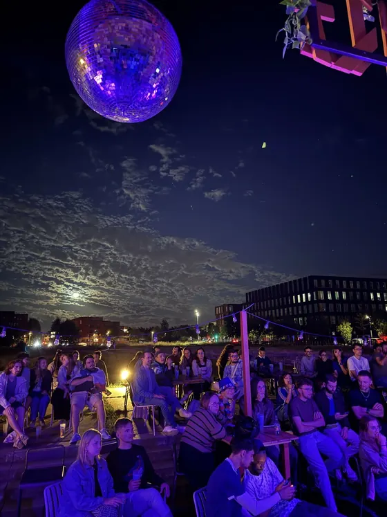 Boule à facettes suspendue au-dessus de la terrasse du Gong de nuit, clientèle attablée sous la pleine lune