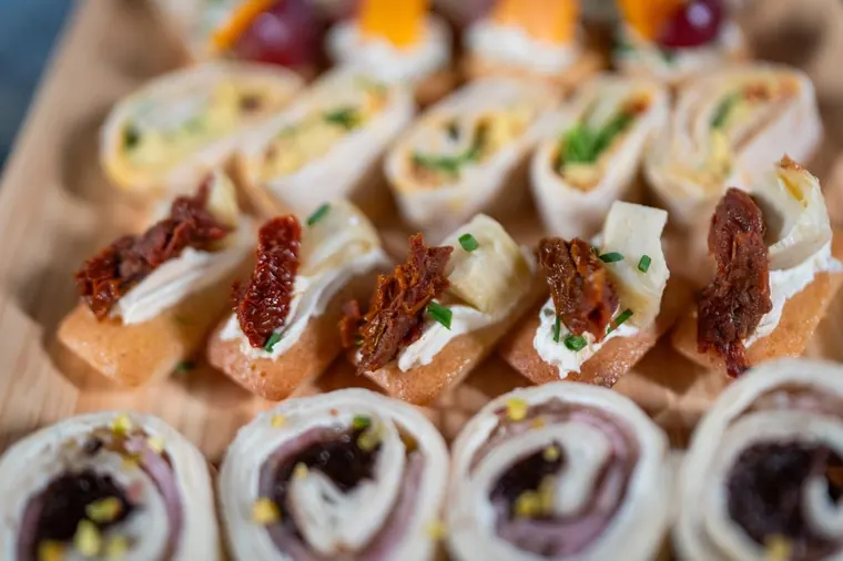 Canapés et roulés apéritifs dressés sur une planche