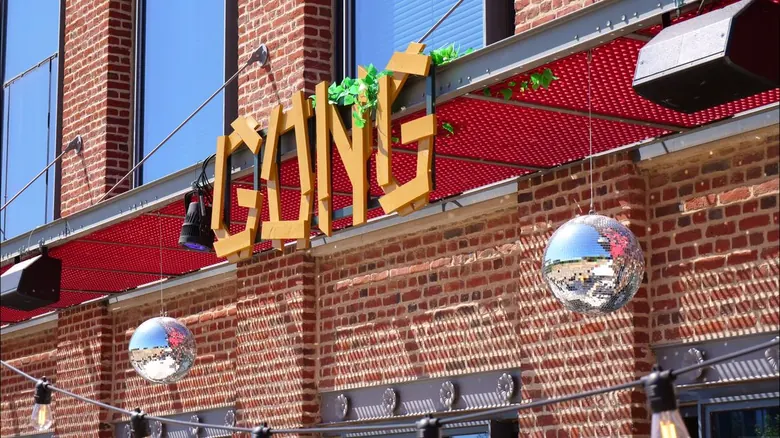 Enseigne en bois GONG et boules à facettes accrochées à la façade en briques