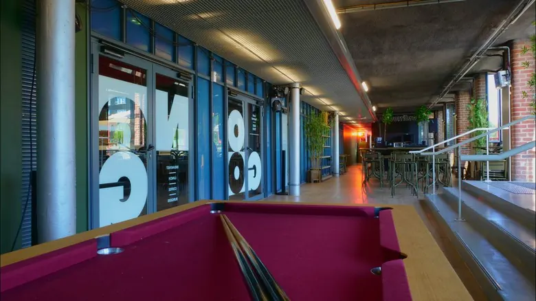 Table de billard au premier plan, couloir menant au bar intérieur du Gong