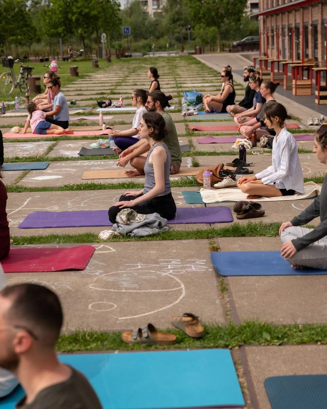 Séance de yoga collective en plein air sur le parvis du Gong, tapis colorés au sol